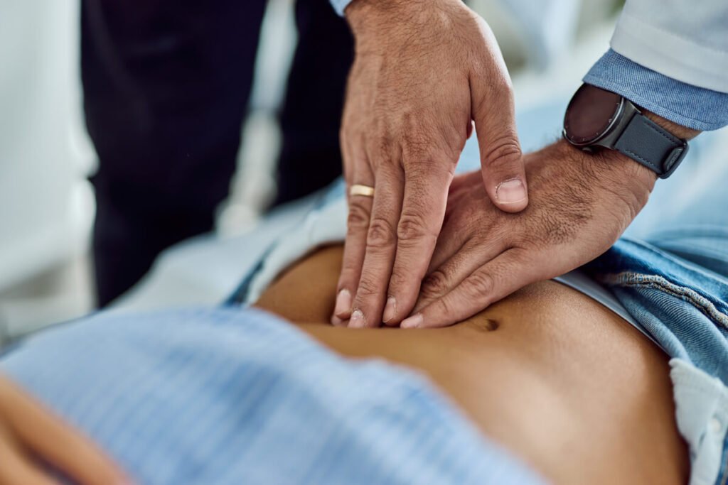Médecin généraliste réalisant une palpation de l'abdomen d'un patient pour vérifier son transit intestinal
