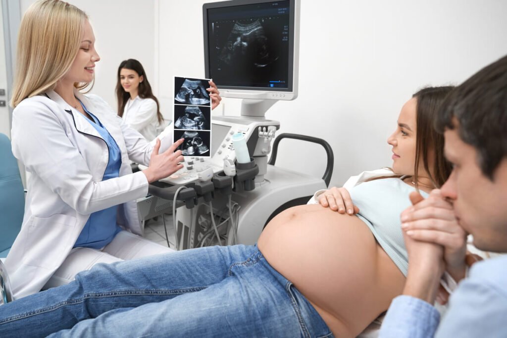 Médecin gynécologue montrant l'écran d'une échographie obstétricale à un couple.