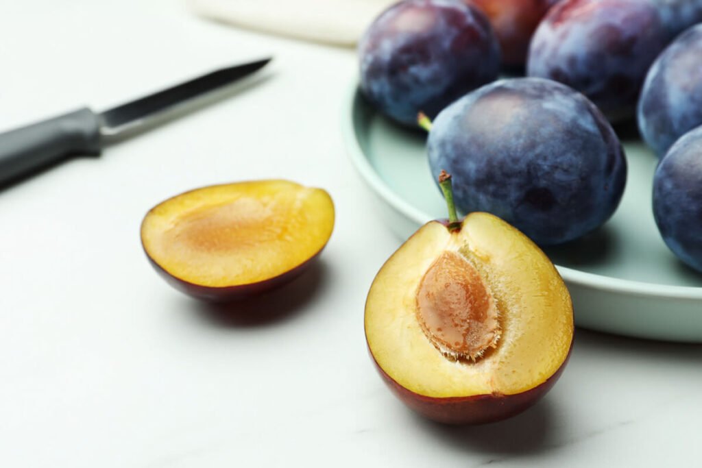 Gros plan sur un noyau de prune lisse reposant sur une table près d'une assiette de fruits frais