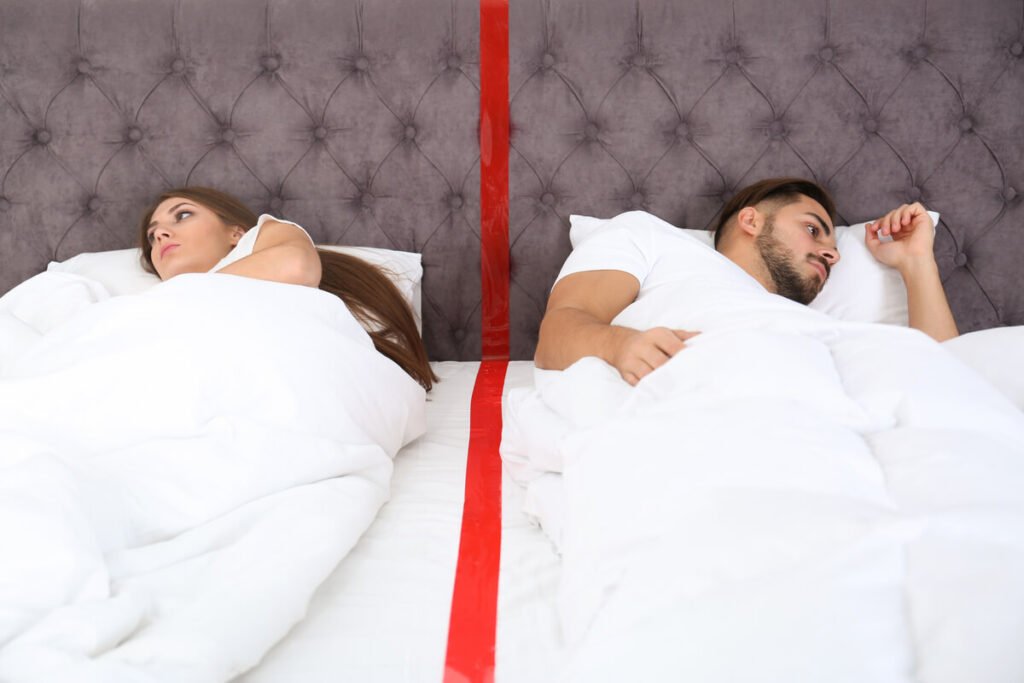 Pourquoi je ne supporte plus de dormir avec mon mari et quelles solutions ? 2 Couple dormant séparément illustrant une tension liée à l'incompatibilité nocturne.