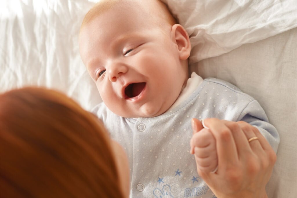 Lavage de nez au lait maternel : le remède naturel magique pour bébé 3 Un nouveau-né qui sourit sur le dos, libéré de son rhume après un soin nasal naturel.