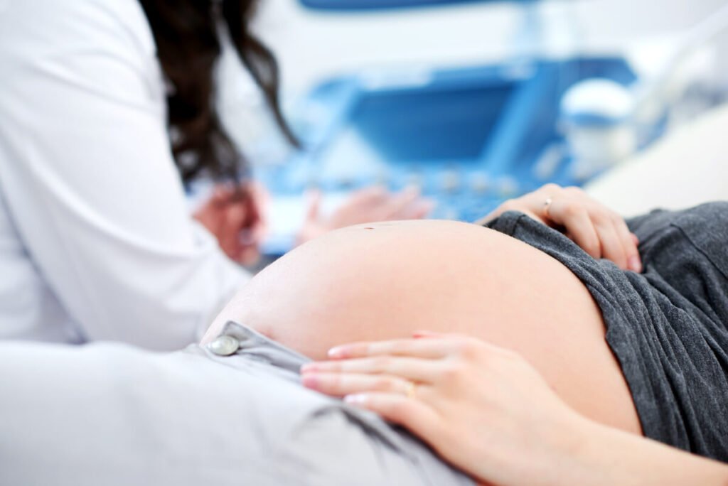 Une sage-femme auscultant le ventre d'une future maman lors d'un rendez-vous médical.
