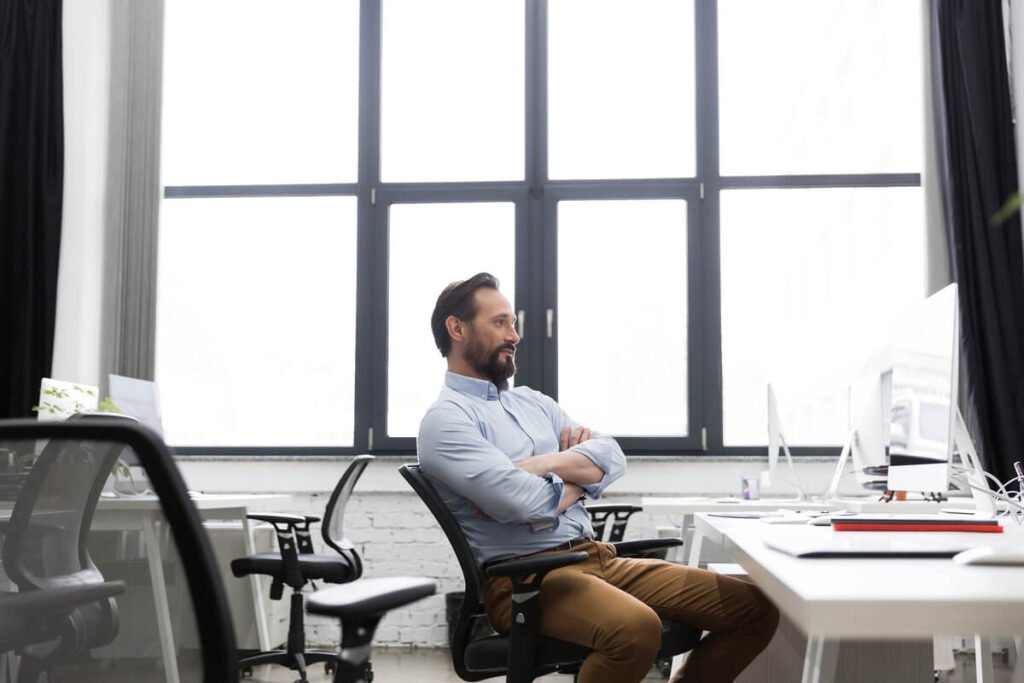 Kyste de Tarlov et travail : aménagements, droits et vie pro 2 Une personne travaillant sur un bureau ergonomique avec un siège adapté pour le dos.