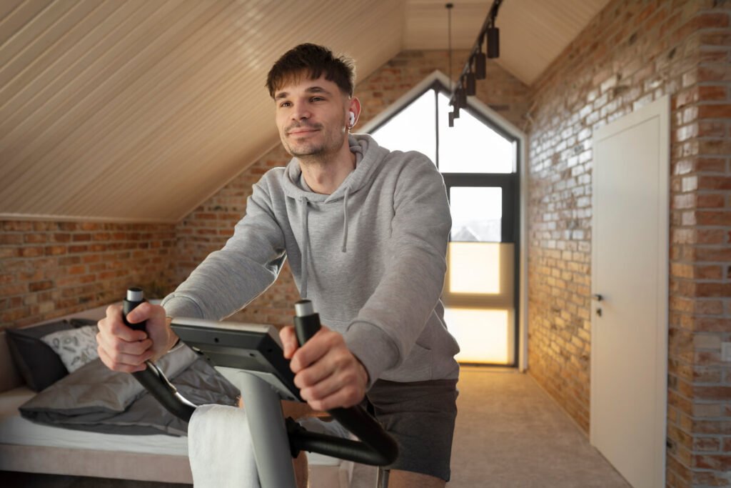 J'ai perdu du poids grâce au vélo d'appartement : témoignage et méthode de sport 2 Une personne souriante s'entraînant sur un vélo d'appartement dans son salon devant sa télévision.