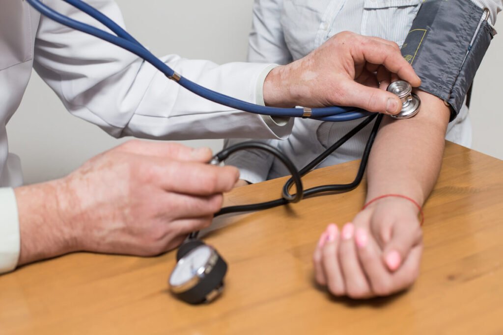Tension pincée : définition, causes physiques et risques de santé 2 Un médecin gonflant un brassard de tensiomètre manuel pour mesurer la tension d'un patient.