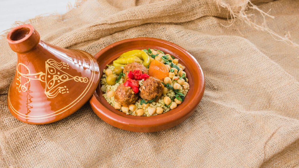 Un plat à tajine traditionnel en terre cuite marron posé sur un plan de travail de cuisine.