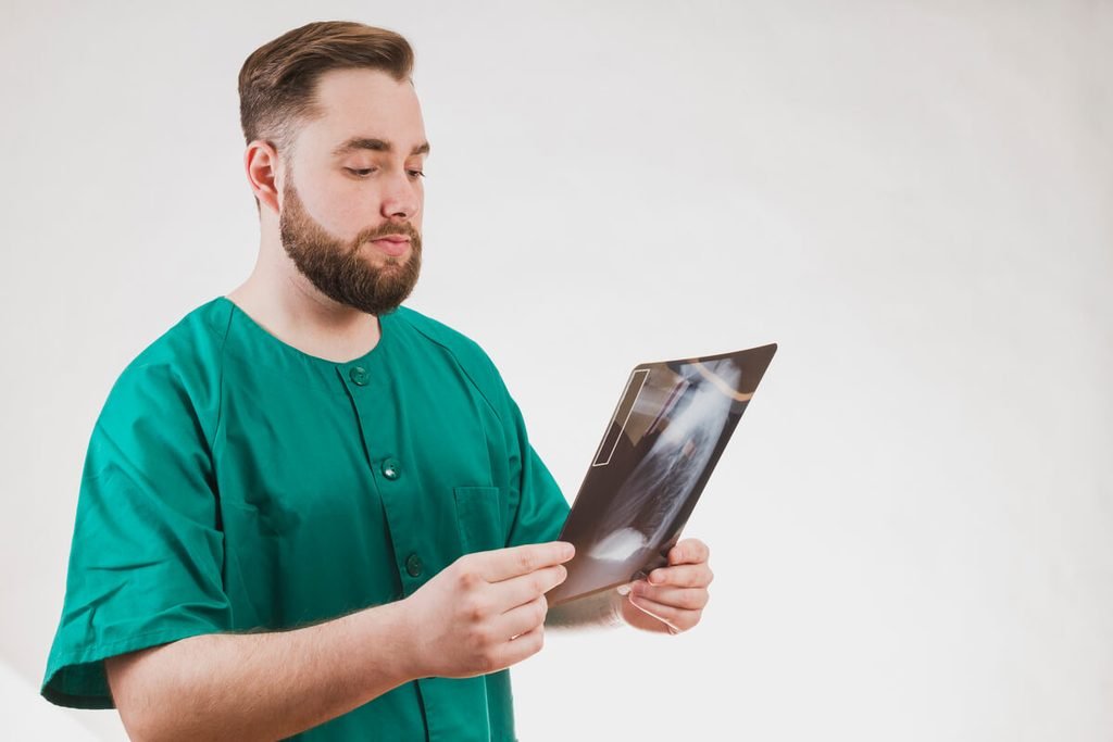 Douleurs 2 ans après arthrodèse lombaire : les causes à envisager 3 Chirurgien orthopédique examinant un scanner du dos pour rechercher un syndrome adjacent.