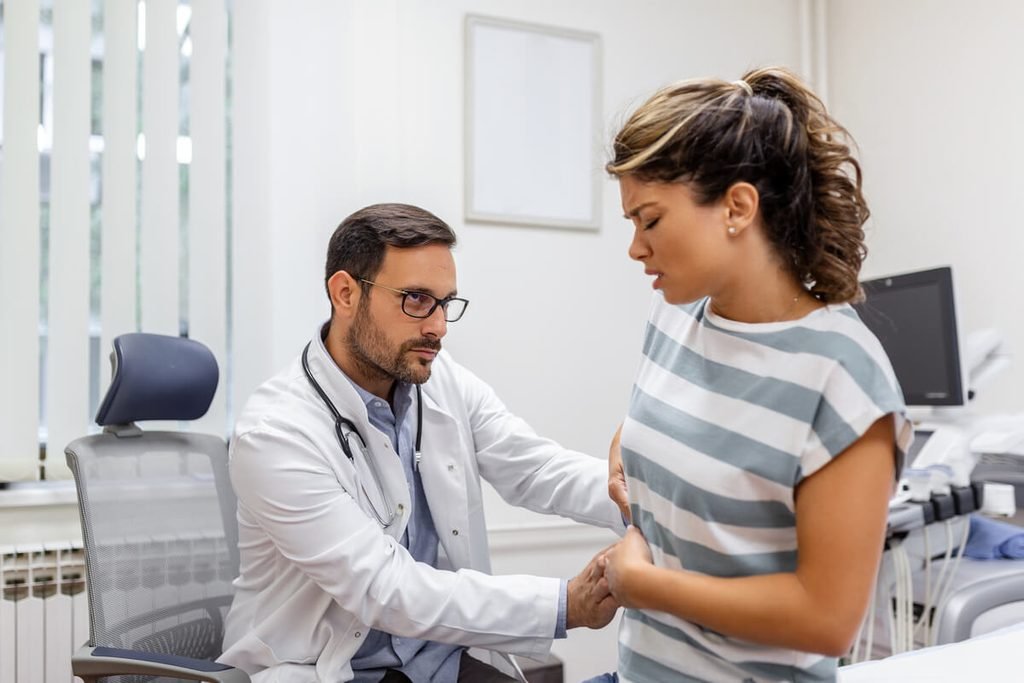 Médecin examinant un patient pour identifier l'origine de maux de ventre chroniques.