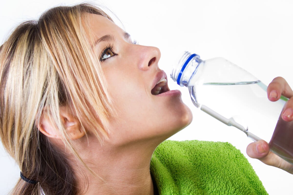 Personne buvant une grande bouteille d'eau tout en observant un gonflement œdémateux à ses chevilles.