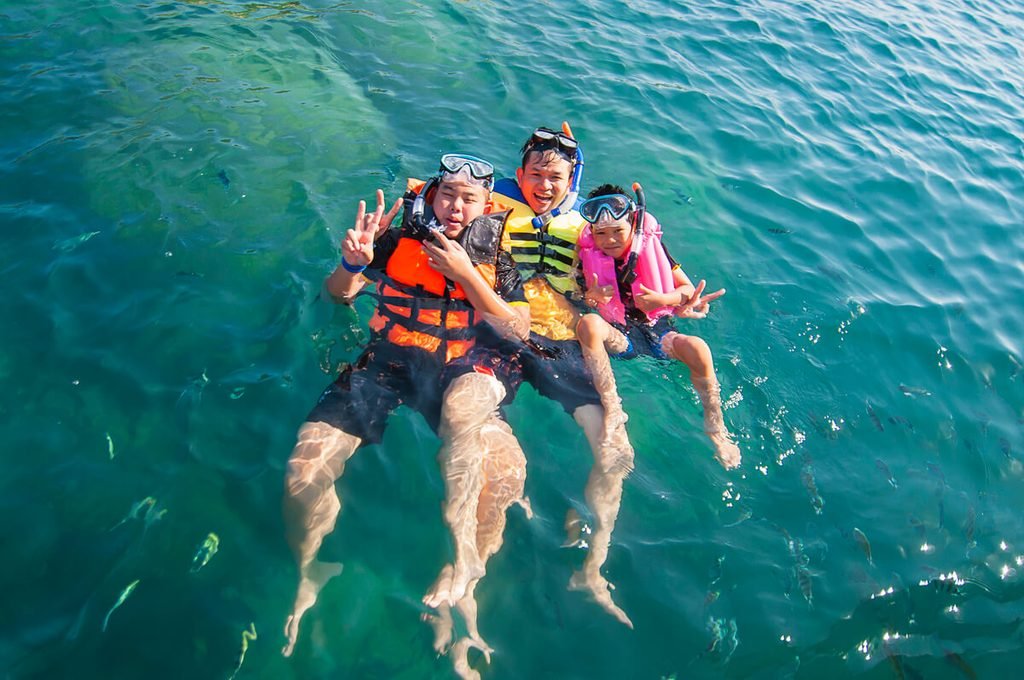 Famille équipée de gilets de flottaison observant le courant d'une rivière avant la baignade.