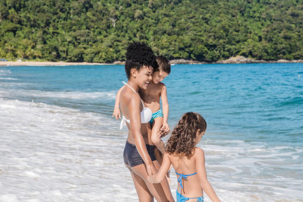Parent surveillant attentivement ses jeunes enfants qui jouent au bord de l'eau sur une plage surveillée.