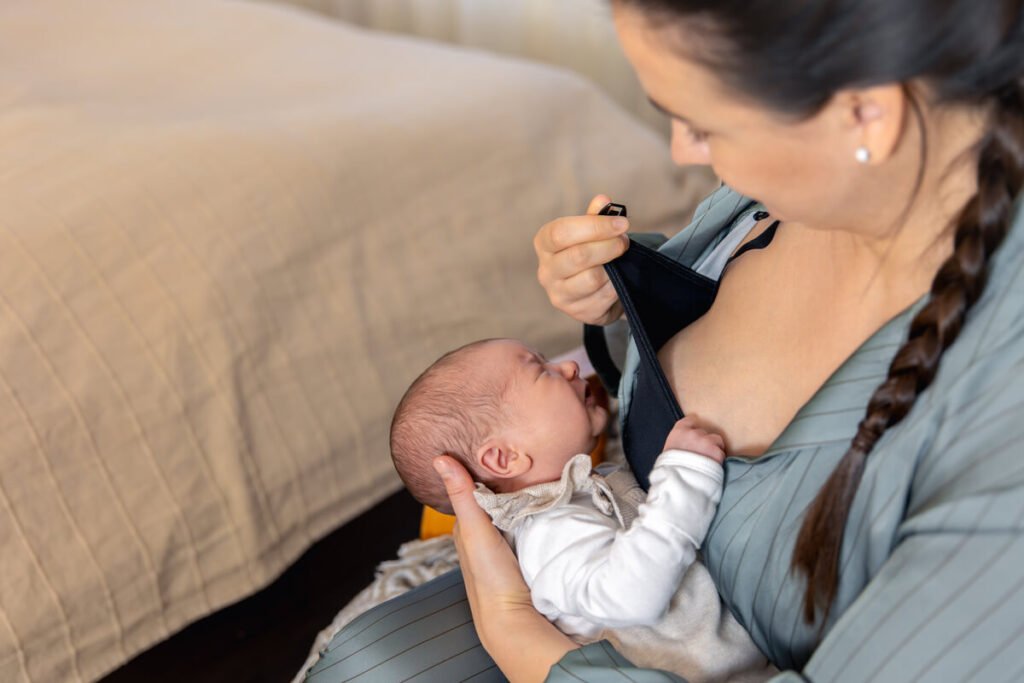 Bébé régurgite et redemande à manger : est-ce normal 2 Nourrisson recrachant du lait sur son bavoir et réclamant à nouveau le biberon en pleurant.