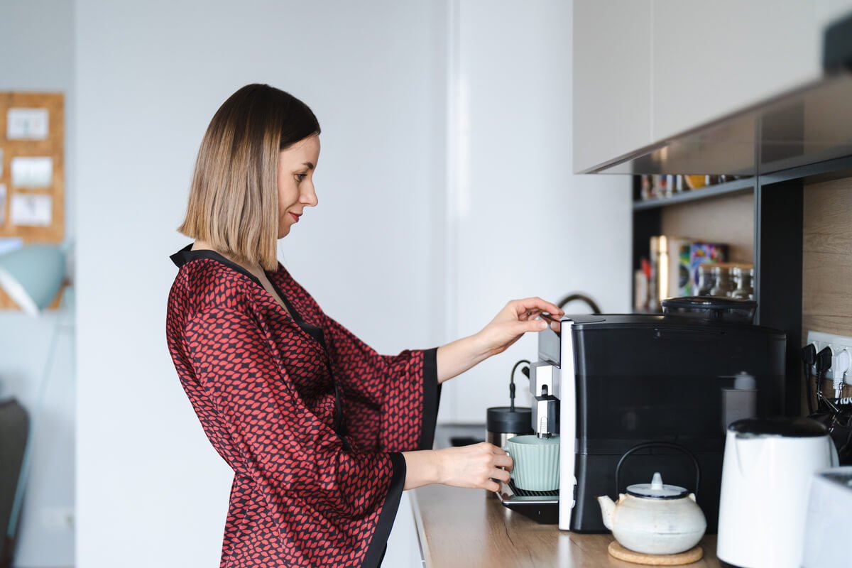 Machine à café avec broyeur à grains De'Longhi posée sur le plan de travail d'une cuisine.