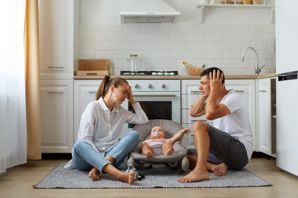 Maman épuisée, je pète un câble : ce n'est pas ta faute 2 Mère de famille submergée par la fatigue assise la tête dans les mains dans une cuisine encombrée.
