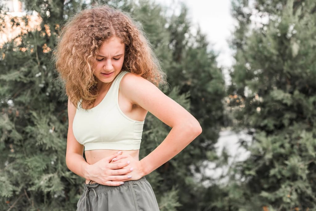 Personne portant la main à son estomac en raison de reflux gastriques et d'acidité.