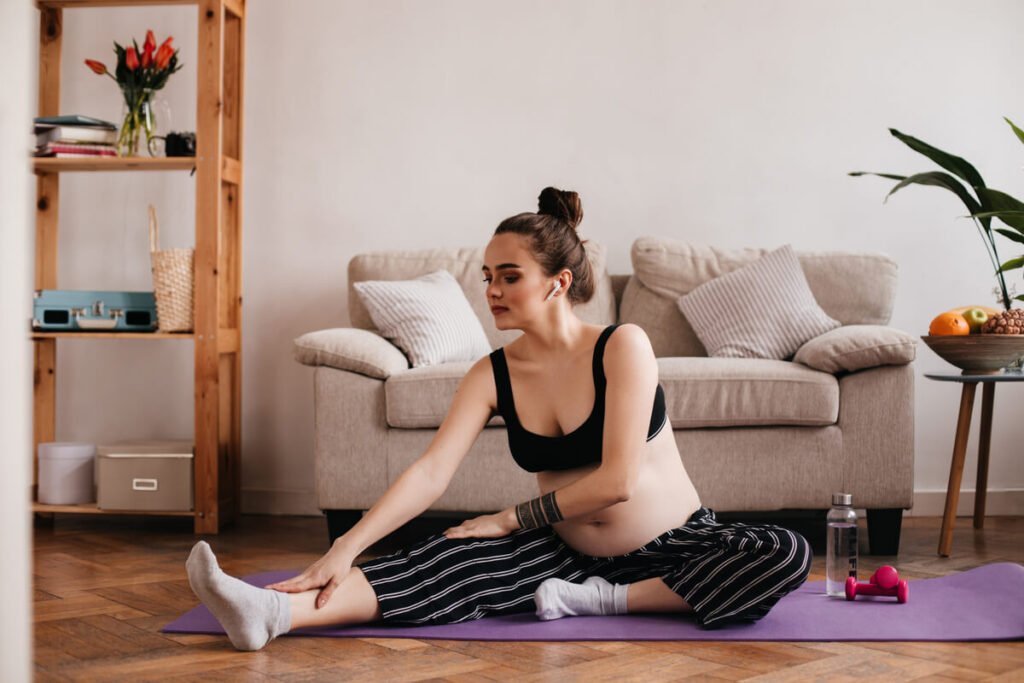 Jeune maman réalisant des étirements et des exercices de respiration sur un tapis de fitness chez elle.