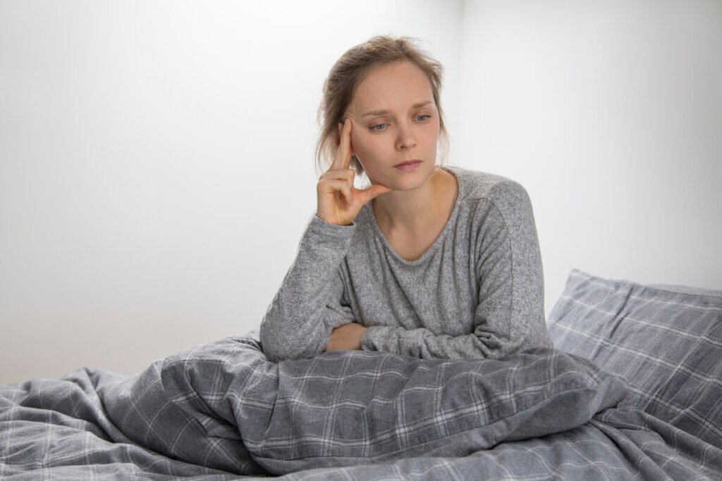 Toujours fatigué ? Les causes les plus fréquentes et les solutions 2 Personne assise au bord de son lit le matin montrant des signes de fatigue persistante.