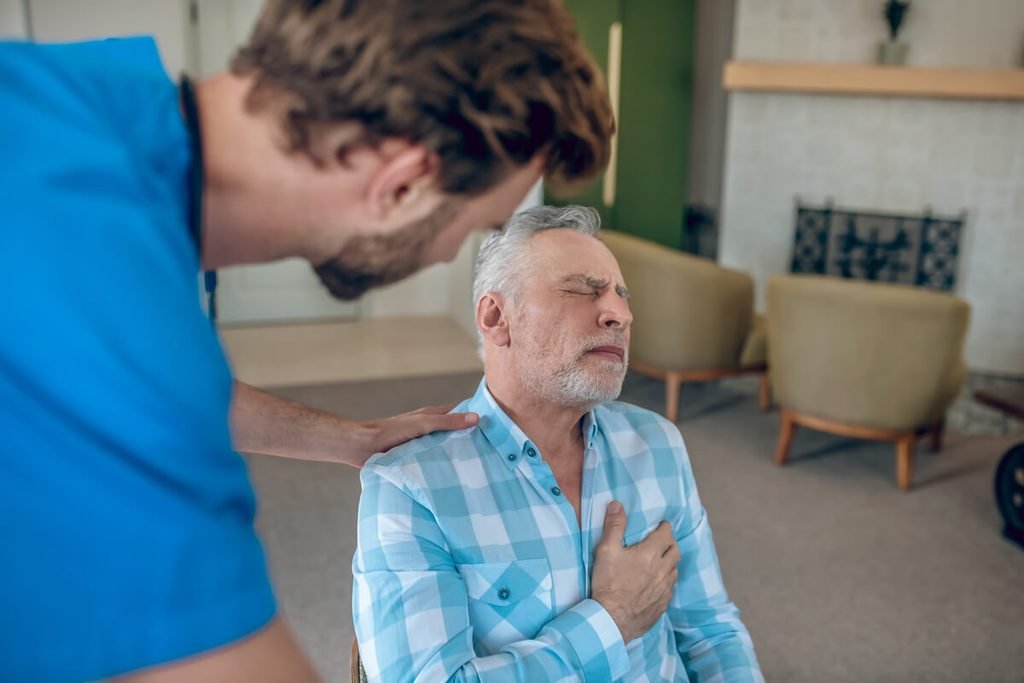 Palpitations, essoufflement, douleur thoracique : quand passer un électrocardiogramme ? 3 Adulte posant la main sur son torse en ressentant une douleur thoracique et un essoufflement anormal.